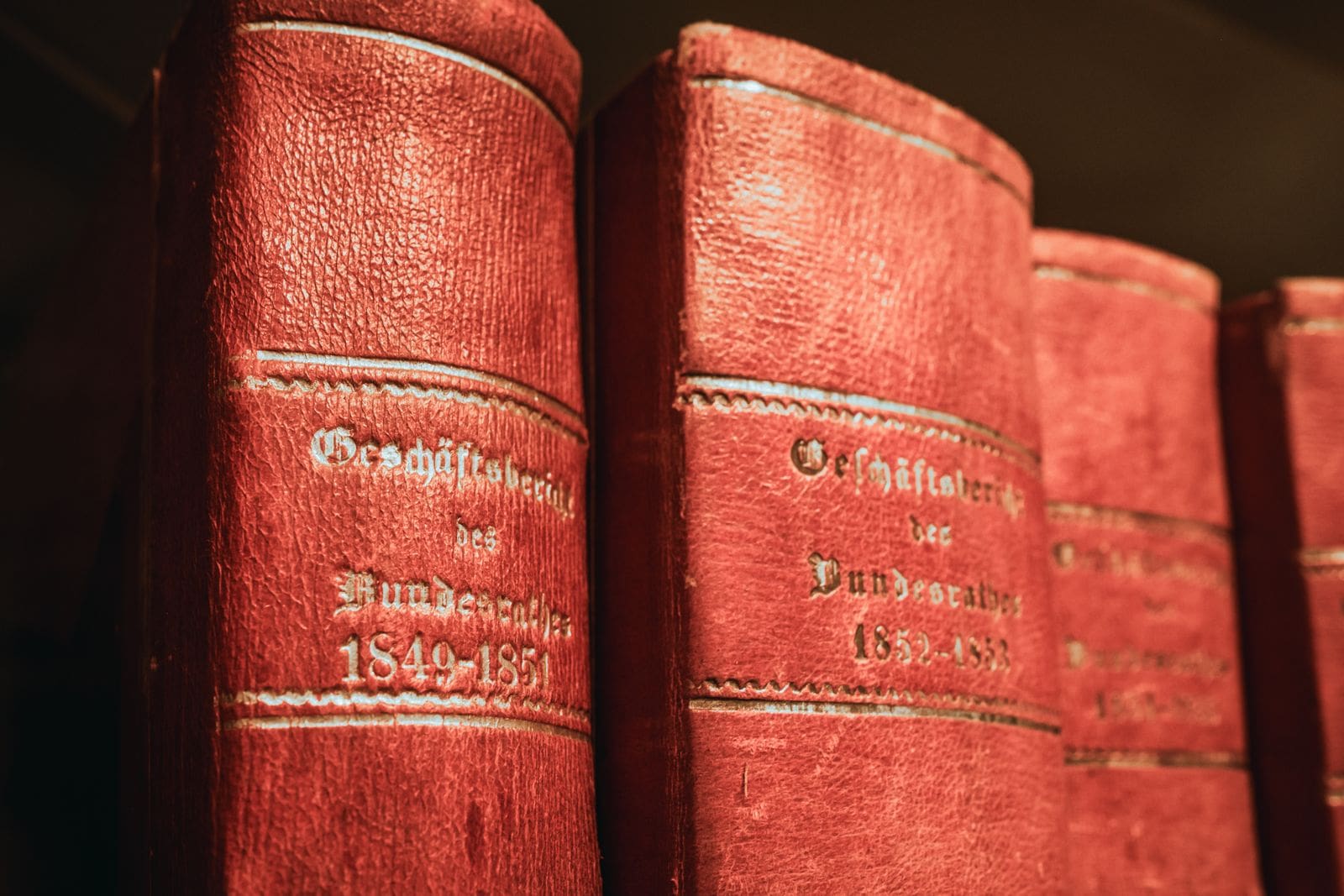 Old red leather-bound reference books on a library shelf