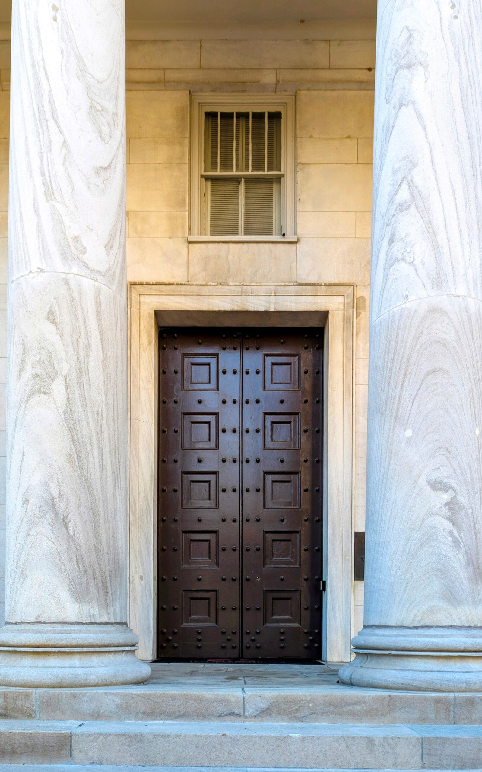 Stone columns and heavy wooden doors at a courthouse entrance, the kind of building where criminal cases from Erie, Pennsylvania are heard