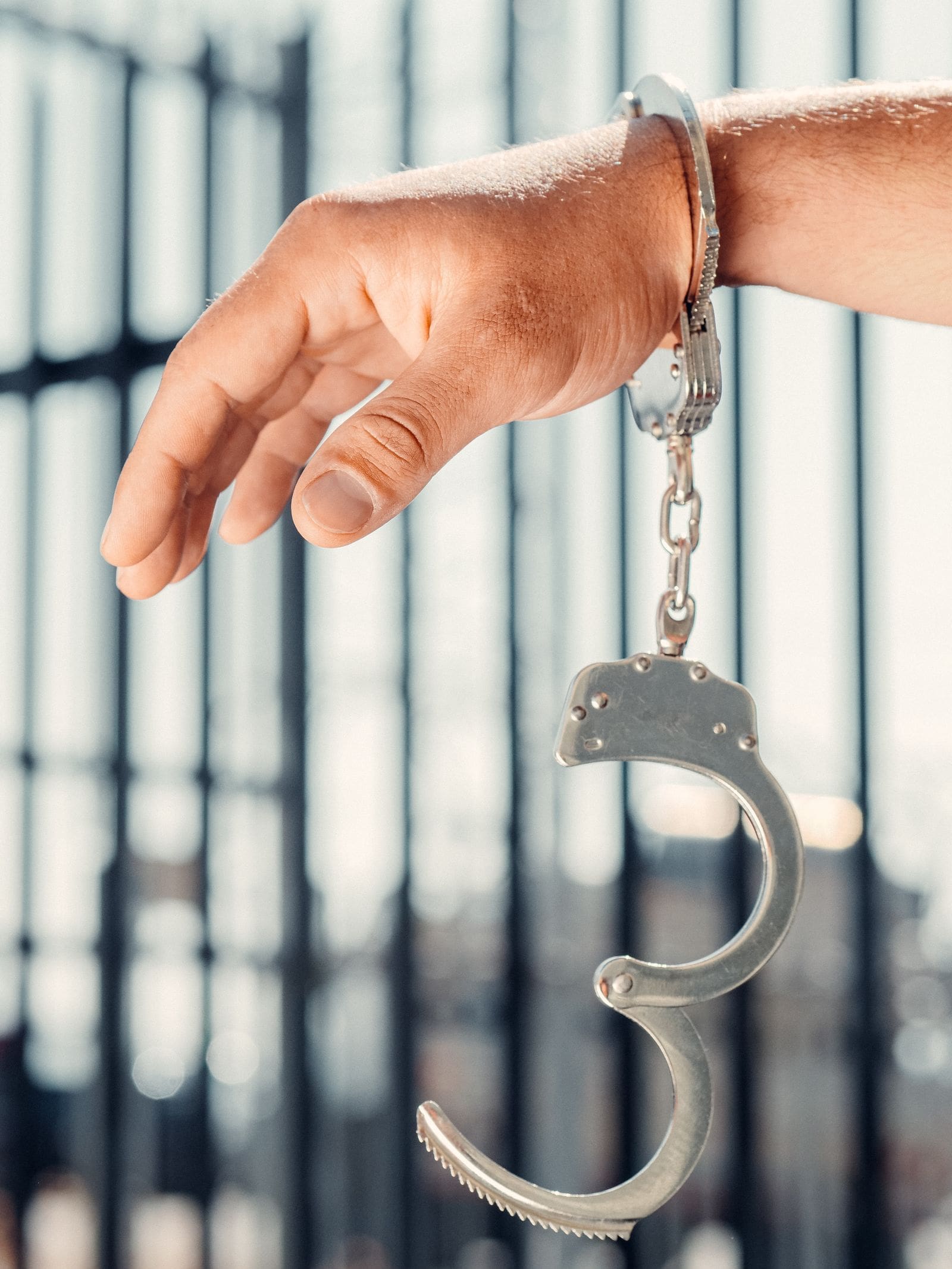 A wrist in handcuffs against a barred background, the reality behind a criminal charge in Erie, Pennsylvania
