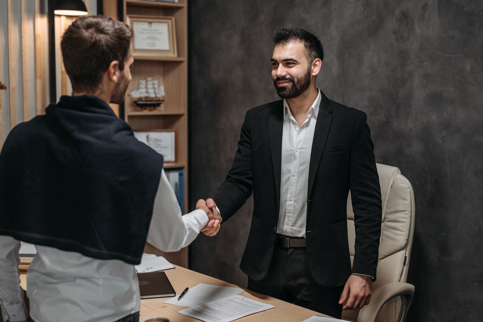 An attorney and a client shake hands after meeting in an office