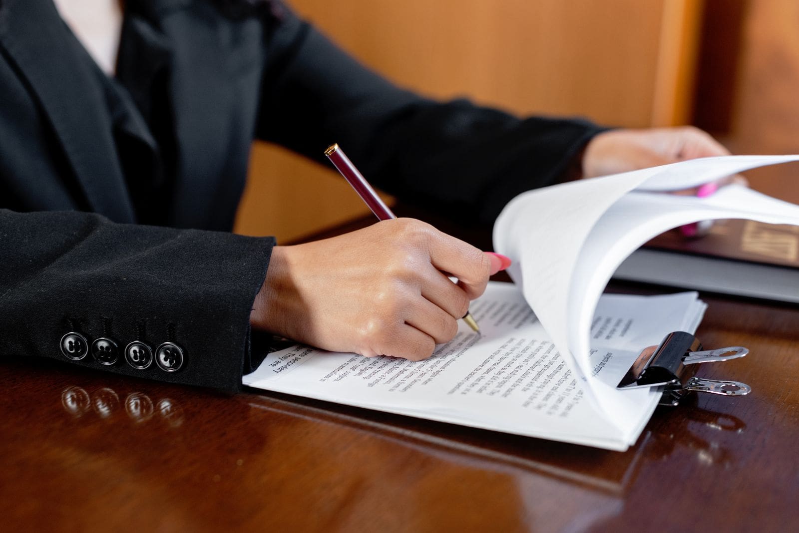 A person signing and reviewing legal documents at a desk